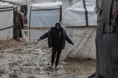 Internally displaced Palestinians walk outside their tents on a windy day west of Deir al-Balah, central Gaza Strip-stock-foto