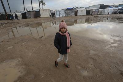 Internally displaced Palestinians walk outside their tents on a windy day west of Deir al-Balah, central Gaza Strip-stock-foto