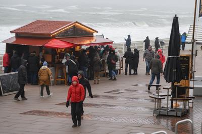 31.12.2024, Westerland --- Touristen stehen auf der Promenade von Westerland auf der Nordseeinsel Sylt an einem Gl?hwein-stock-foto