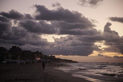 Palestinians walk on the beach during sunset on the last day of 2024 in Deir al-Balah in the central Gaza Strip, on 31 December 2024. Heavy rains in the Gaza-stock-foto