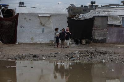 Internally displaced Palestinians walk outside their tents on a windy day west of Deir al-Balah, central Gaza Strip-stock-foto