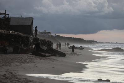 Palestinians walk on the beach during sunset on the last day of 2024 in Deir al-Balah in the central Gaza Strip, on 31 December 2024. Heavy rains in the Gaza-stock-foto