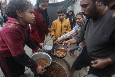 Displaced Palestinians line up to receive food from a charity soup kitchen at a displacement camp in Deir al-Balah in the central Gaza Strip-stock-foto