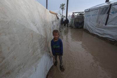 Internally displaced Palestinians walk outside their tents on a windy day west of Deir al-Balah, central Gaza Strip-stock-foto