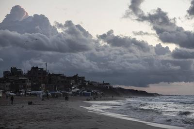 Palestinians walk on the beach during sunset on the last day of 2024 in Deir al-Balah in the central Gaza Strip, on 31 December 2024. Heavy rains in the Gaza-stock-foto