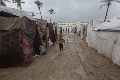 Internally displaced Palestinians walk outside their tents on a windy day west of Deir al-Balah, central Gaza Strip-stock-foto