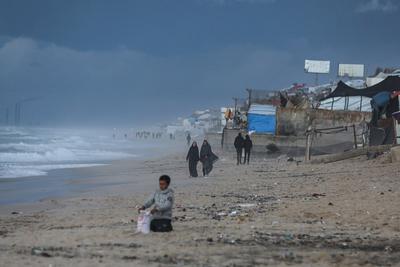 Palestinians walk on the beach during sunset on the last day of 2024 in Deir al-Balah in the central Gaza Strip, on 31 December 2024. Heavy rains in the Gaza-stock-foto