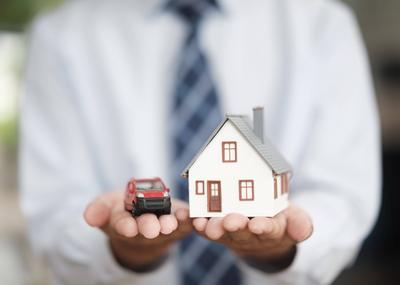 Real Estate Agent Holding House and Car Models Symbolizing Property and Vehicle Insurance Hands holding car and house. H-stock-photo