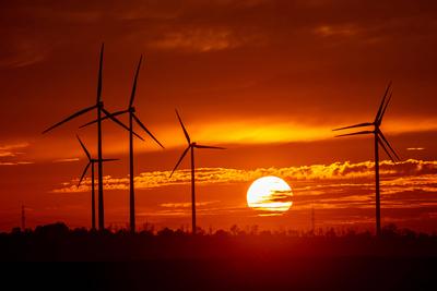 Windraeder stehen vor der untergehen Sonne und dem roetliche gefaerbten Abendhimmel am 10.10.2022 bei Gebesee. Wind turb-stock-photo