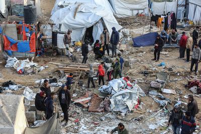 Palestinians inspect the damaged area following an Israeli attack on tents housing the displaced Palestinians in Deir al-Balah, Gaza-stock-foto