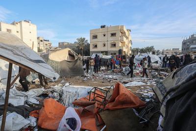 Palestinians inspect the damaged area following an Israeli attack on tents housing the displaced Palestinians in Deir al-Balah, Gaza-stock-foto