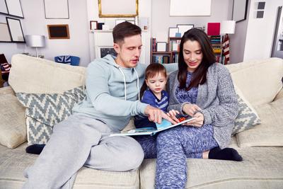 Family reading a book together on the couch LUXYIMAGES_05429 Copyright: xImageSourcex-stock-photo