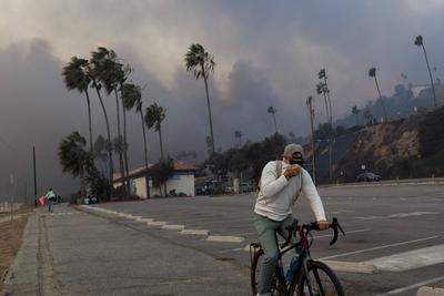 PACIFIC PALISADES, CA - JANUARY 07: A resident rides through smoke from a brush fire pushed by gusting Santa Ana winds o-stock-foto