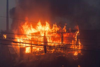 PACIFIC PALISADES, CA - JANUARY 07: Flames from a brush fire pushed by gusting Santa Ana winds burn a home on January 7,-stock-foto