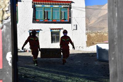 DINGRI, CHINA - JANUARY 10: Firefighters move remained possessions of quake-affected residents from a damaged house on J-stock-foto