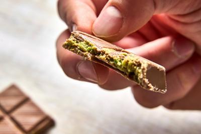 Bavaria, Germany - November 22, 2024: A man holds a single piece of the luxurious Dubai Chocolate, with pistachios and a-stock-foto