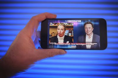 Hand h?lt ein Mobiltelefon auf dem Das Gespr?ch von Alice Weidel mit Elon Musk auf der Plattform X zu sehen ist. *** Hand holds a mobile phone on which Alice Weidel's conversation with Elon Musk on Platform X can be seen.-stock-foto