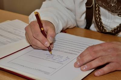 modisch gekleideter Mann unterschreibt Urkunde PUBLICATIONxINxGERxSUIxONLY 1077401911-stock-foto