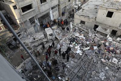 Palestinian residents inspect the area among the rubbles of demolished buildings following an Israeli attack-stock-foto