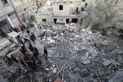 Palestinian residents inspect the area among the rubbles of demolished buildings following an Israeli attack-stock-foto