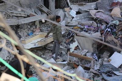 Palestinian residents inspect the area among the rubbles of demolished buildings following an Israeli attack-stock-foto