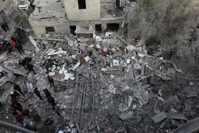 Palestinian residents inspect the area among the rubbles of demolished buildings following an Israeli attack-stock-foto