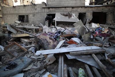 Palestinian residents inspect the area among the rubbles of demolished buildings following an Israeli attack-stock-foto