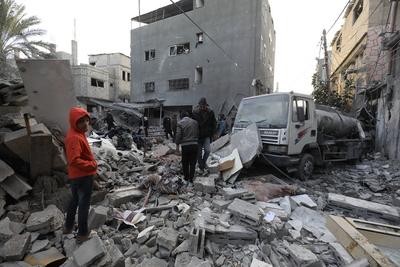 Palestinian residents inspect the area among the rubbles of demolished buildings following an Israeli attack-stock-foto