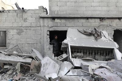 Palestinian residents inspect the area among the rubbles of demolished buildings following an Israeli attack-stock-foto