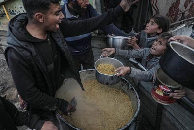 Palestinians gather to receive food cooked by a charity kitchen, before a ceasefire between Hamas and Israel takes effect, in Khan Younis-stock-foto