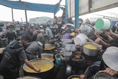 Palestinians gather to receive food cooked by a charity kitchen, before a ceasefire between Hamas and Israel takes effect, in Khan Younis-stock-foto