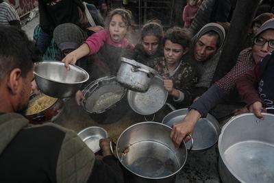Palestinians gather to receive food cooked by a charity kitchen, before a ceasefire between Hamas and Israel takes effect, in Khan Younis-stock-foto