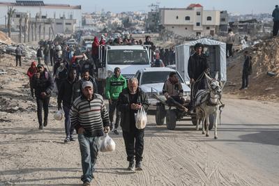 Displaced Palestinians travel in vehicles past rubble, as they attempt to return to their homes, in Rafah-stock-foto