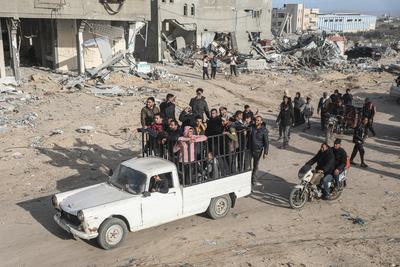 Displaced Palestinians travel in vehicles past rubble, as they attempt to return to their homes, in Rafah-stock-foto