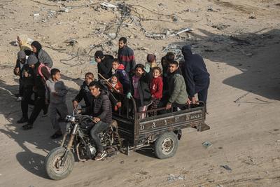 Displaced Palestinians travel in vehicles past rubble, as they attempt to return to their homes, in Rafah-stock-foto