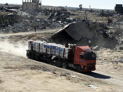 Security guards sit atop trucks carrying humanitarian aid coming in from the Kerem Shalom border crossing (also known as Karem Abu Salem-stock-foto