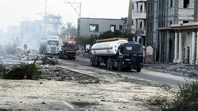 Security guards sit atop trucks carrying humanitarian aid coming in from the Kerem Shalom border crossing (also known as Karem Abu Salem-stock-foto