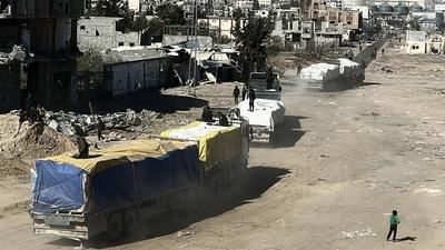 Security guards sit atop trucks carrying humanitarian aid coming in from the Kerem Shalom border crossing (also known as Karem Abu Salem-stock-foto