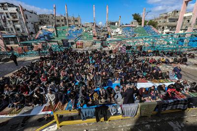 Palestinians perform Friday prayers at the Al-Bureij Services Club stadium, which was destroyed by Israeli airstrikes on the Al-Burei-stock-photo