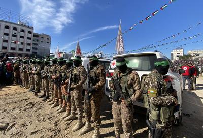 Hamas fighters secure an area in a square before handing over four Israeli hostages to a Red Cross team in Gaza-stock-foto