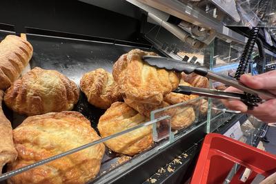 Backwaren aus der Backtheke im REWE Supermarkt. Mit einer Zange wird Gebaeck aus der Theke entnommen. *** Baked goods fr-stock-foto