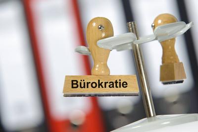 B?rokratie In einem B?ro mit Aktenordner h?ngt ein Holzstempel mit dem Aufdruck: B?rokratie *** Bureaucracy A wooden sta-stock-foto