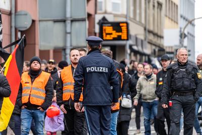 Aschaffenburg, Bavaria, Germany - January 26, 2025: A police officer talks to stewards dressed in orange vests as the de-stock-foto
