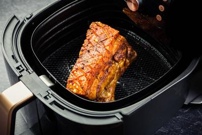 Cooking crispy pork belly in airfryer. Fast and easy crispy food cooking with little or no fat by circulating hot air in-stock-foto