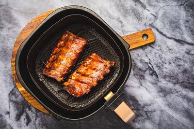Modern cooking - preparing juicy spare ribs with honey sauce in airfryier Modern cooking - preparing juicy spare ribs wi-stock-foto