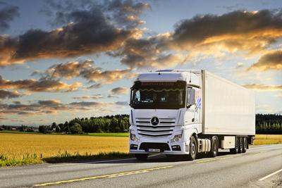 White Mercedes-Benz Semi Trailer Transport at Dusk White Mercedes-Benz Actros 1845 truck pulls FRC semi trailer on highw-stock-photo