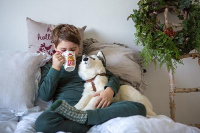 23 November 2024: A child with a warm mug on the sofa - a symbolic image for colds, recovery and care during the cold se-stock-foto