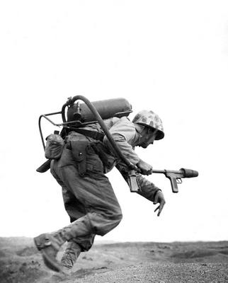 USA / Japan: A US marine carrying a flame-thrower sprints towards a Japanese pillbox at Motoyama Airfield, Iwo Jima, Feb-stock-photo