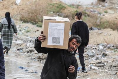 Palestinians carry boxes of aid provided by UNRWA, amid a ceasefire between Hamas and Israel, in Gaza City-stock-foto