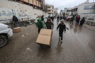 Palestinians carry boxes of aid provided by UNRWA, amid a ceasefire between Hamas and Israel, in Gaza City-stock-foto